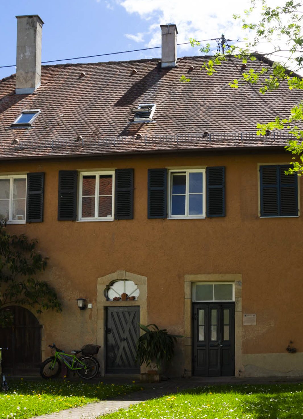 Foto, Teil des alten Schulhaus, Eingang mit alter barocker Eingangstür und großer später eingefügter Tür für die Schüler*innen